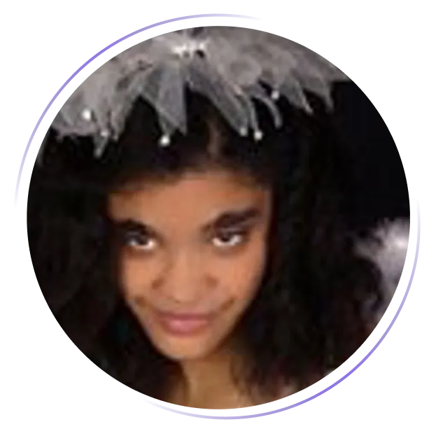 Girl wearing a white feathered headpiece and smiling with a mischievous expression.