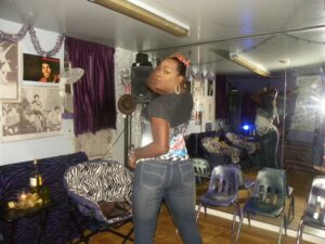 Person posing confidently indoors near a mirror and furniture.