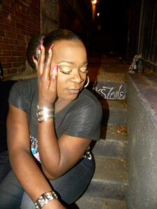 Person posing with eyes closed, resting head on hand outdoors.