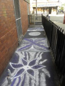 Sidewalk decorated with white floral and geometric chalk art.