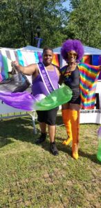 Two people posing with colorful flags at an outdoor event.