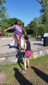 Two girls playing outdoors, one balancing on a stone ledge.