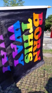A colorful pride flag with the words 'BORN THIS WAY' outdoors.