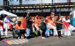 A group of people cleaning a street under a bridge, holding trash bags.
