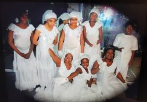 Group of women dressed in white traditional attire posing together.