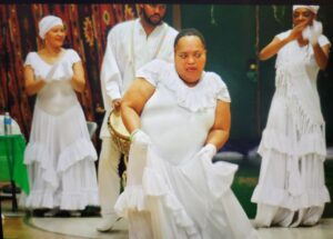 A joyful woman in white dancing with others in white attire.