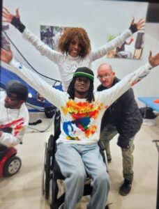 Group photo with a person in a wheelchair and friends posing happily.