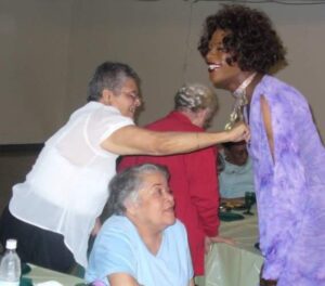 Two women interacting warmly in a lively indoor setting.