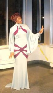Person in a stylish white dress with red accents striking a pose indoors.