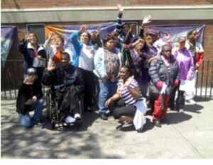 A joyful group posing outdoors with smiles and raised hands.