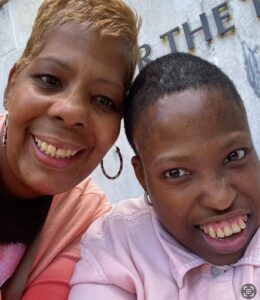 Two women smiling closely for a selfie outdoors.