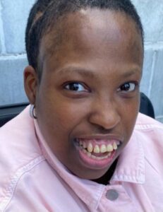 Smiling young person with a light pink jacket.