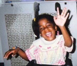 A joyful child laughing and waving indoors.