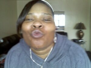 Woman making a playful kissy face at the camera indoors.