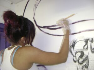 Woman painting an artistic mural on a wall.