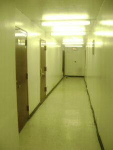 Dimly lit corridor with multiple closed doors on one side.