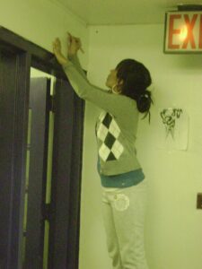 Young person reaching up near a doorway inside a building.