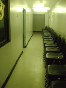 Empty waiting room with chairs lined up along the wall.
