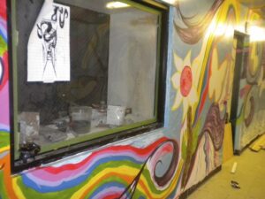 Colorful psychedelic mural with a silhouetted figure on a wall near a hallway.